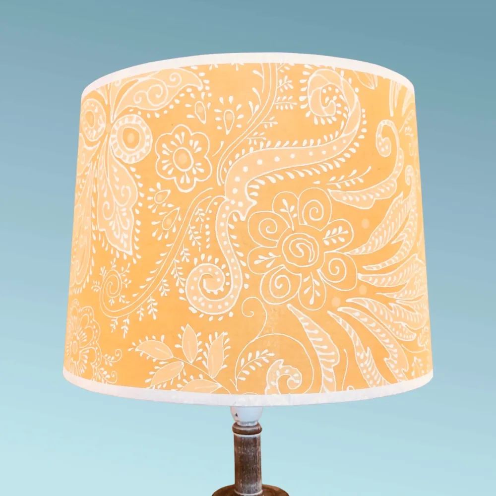 Abat jour tambour contrecollé sur un voile de coton jaune à motifs baroques.